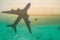 Concept of airplane travel to exotic destination with shadow of commercial airplane flying above beautiful tropical beach. Beach