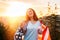 The concept of American National Holidays. A patriotic girl holds an American flag in her hands. Sunset in the