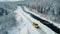 Concept of auto travel during winter holiday season. One yellow car is driving on snow along mountain road near forest and stormy