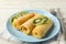 Concept of breakfast with plate of crepes rolls with kiwi slices on wooden table