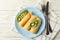 Concept of breakfast with plate of crepes rolls with kiwi slices on wooden table