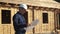 Concept building architect slow motion video. man builder in a helmet stands at a construction holding a scheme house