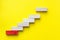 Concept of building success foundation. Red wooden block stacking as step stair, Success in business growth concept on yellow