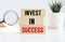 Concept of building success foundation. Wooden blocks on the stack of wooden blocks. Text 'invest in success