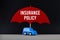 Concept of car insurance. Blue car under red umbrella with text Insurance Policy