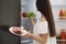 Concept of choice between healthy and junk food. Woman holding plate with sweets near refrigerator in kitchen, focus on hand