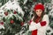 The concept of Christmas and the new year. Winter vibes. The girl in the red and gloves hat near the festive Christmas tree.