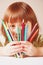 Concept: Colours of  my life. Humorous photo of great artist. Portrait of cute little child girl with colored pencils