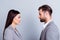 Concept of confrontation in business. Close up photo of two young serious confident people standing face-to-face to each other