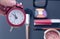 Concept cropped image with cosmetic and make up products. Quick make-up. Red retro clock. Selective focus