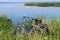 The concept of cycling trips in the summer. Two bicycles are standing by the lake against the blue sky, close-up