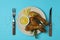 Concept of delicious eating with plate of roast chicken drumsticks on blue background