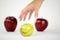 Concept of diversity: a woman`s hand is about to grab the only green apple among the other red ones