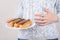 Concept of eating too much sweet food. Cropped close-up photo of woman holding plate with delicious glazed cupcakes holding hand