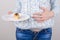 Concept of eating too much of sweets. Cropped closeup photo of cheerful girl enjoying eating sweets holding almost empty plate in