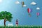 Concept of eco friendly save the environment conservation,couple standing in the meadow and looking to hot air balloon flying