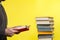 Concept of education. A man holds a book in his hands and reads it. Nearby is a stack of books. Yellow background