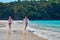 Concept entertainment children on the beach. Two laughing boys run on the turquoise sea beach on background the tropical jungle.