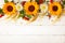 Concept of fall harvest or Thanksgiving day. Autumn composition with wheat ears, sunflowers and berries on white wooden table.