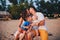 The concept of a family vacation. Young family and two sons sitting on a bench in the evening on a sandy beach. Mom and Dad kiss,