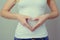 Concept of first weeks pregnancy. Woman`s hands forming heart on