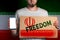 Concept of freedoms and human rights. A man with a cardboard and a phone in his hand. The Flag of Iran. Copy space and mock up