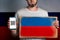 Concept of freedoms and human rights. A man with a cardboard and a phone in his hand. The Flag of Russia. Copy space