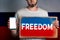 Concept of freedoms and human rights. A man with a cardboard and a phone in his hand. The Flag of Russia. Copy space and mock up