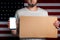 Concept of freedoms and human rights. A man with a cardboard and a phone in his hand. The Flag of USA. Copy space and mock up