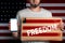 Concept of freedoms and human rights. A man with a cardboard and a phone in his hand. The Flag of USA. Mock up