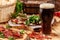 Concept of Georgian restaurant. Glass of black beer with foam stands on wooden table with beer snack