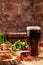 Concept of Georgian restaurant. Glass of black beer with foam stands on wooden table with beer snack