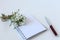 Concept of a good working day: Notepad and pen close-up on a white background with a bouquet of delicate flowers