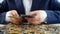 Concept of greedy businessman. Young man in suit sitting at desk full of money and counting big stack of banknotes