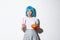 Concept of halloween. Image of attractive skeptical asian girl in blue wig, holding candle and pumpkin, looking serious