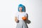 Concept of halloween. Image of scared asian girl in blue wig looking nervous and frightened, holding candle and pumpkin