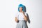 Concept of halloween. Image of scared timid asian girl in blue wig, holding candle and looking at something scary