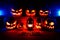 The concept of Halloween. Many Evil Scary Pumpkins in the dark with a blue ice glow. Jack Lantern in the middle of the darkness