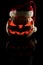 The concept of Halloween and the New Year and Christmas. The evil scary pumpkin Santa in the Santa Claus hat in the dark with ref