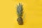 Concept of health with a ananas, pineapple cut in half shot against a yellow background with a blue paper straw in it