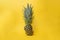 Concept of health with a ananas, pineapple cut in half shot against a yellow background with a orange paper straw in it