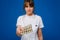 The concept of health care. A young brunette doctor in a white coat on a blue background shows plates with capsules to take