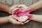 concept healthcare and medicine. hand holding pink ribbon on wood. breast cancer awareness. sign of hope