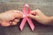 concept healthcare and medicine. two hand holding pink ribbon on wood. breast cancer awareness. sign of hope