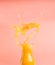 Concept of healthy food, smoothies from oranges and bananas, splashes and drops fly out of bottle, on a pink background, space