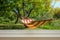 Concept for holiday and lazy days. Hammock in a sunny green garden blurred in the