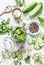 Concept of home canning. Jar of pickled cucumbers and ingredients on a light background, top view