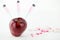 Concept: human GMO manipulation of nature and relative poisoned fruits. Close-up of an apple contaminated with a syringe threaded