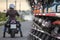 Concept image of costs for maintenance of motorcycle and apparel for motorcyclists, woman on bike near blurred shop stalls with