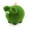 Concept image - Saving Money with a green life style. A bank note being stuck into a green grass  piggybank with eyes made from da